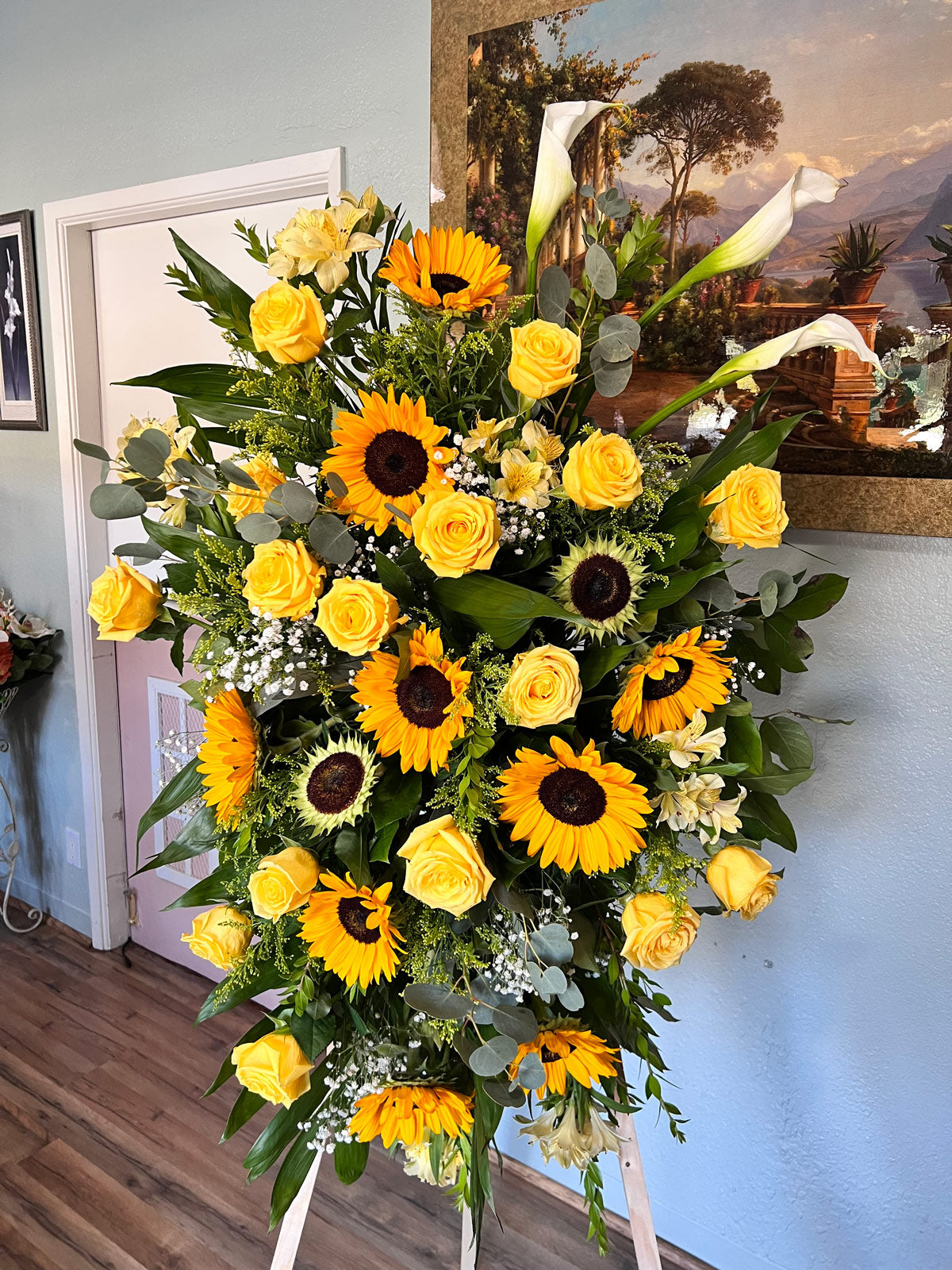 yellow roses, sunflowers, and leaves on stand